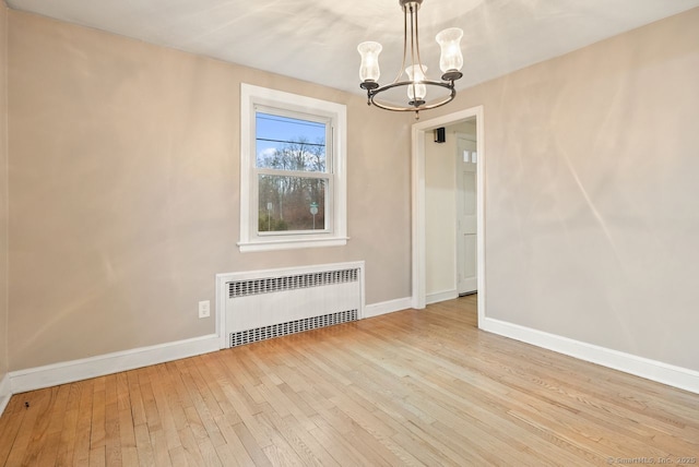 unfurnished dining area with an inviting chandelier, radiator, and light hardwood / wood-style flooring