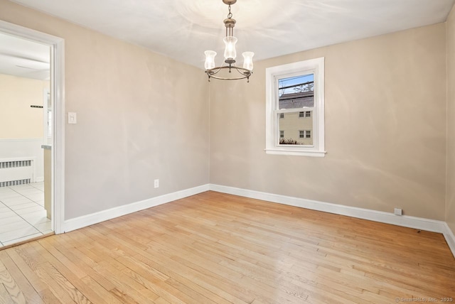 spare room featuring radiator, a chandelier, and light wood-type flooring