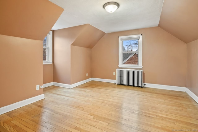 bonus room featuring radiator, vaulted ceiling, and light hardwood / wood-style floors