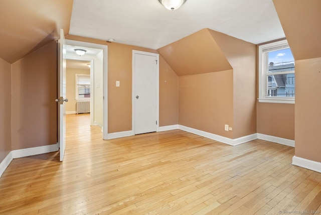 bonus room with lofted ceiling, radiator, and light wood-type flooring