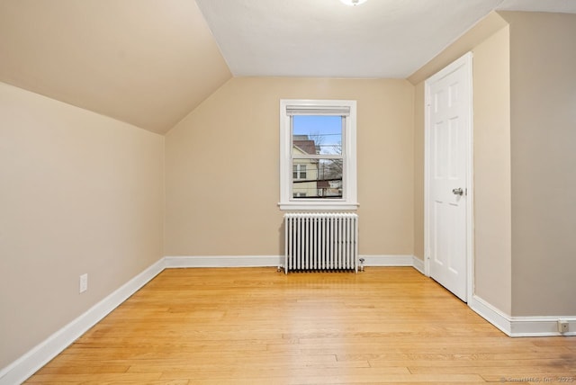 bonus room featuring radiator, light hardwood / wood-style flooring, and vaulted ceiling