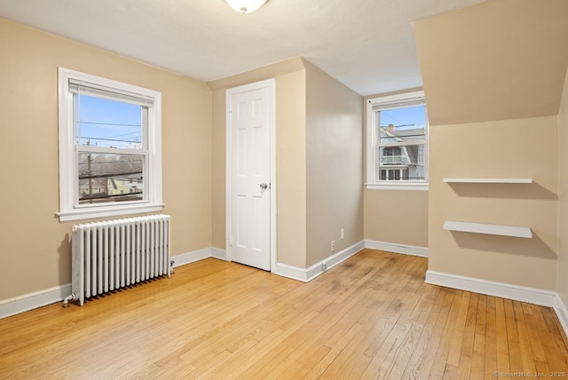 bonus room with radiator heating unit and light hardwood / wood-style flooring