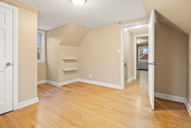 bonus room with lofted ceiling, radiator, and light wood-type flooring