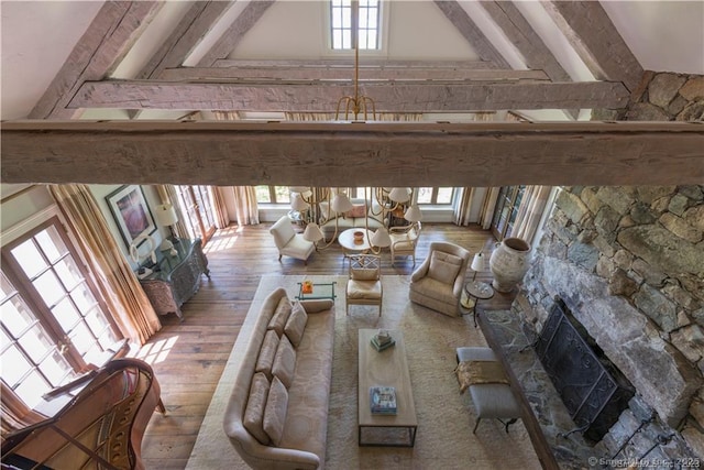 unfurnished living room with hardwood / wood-style flooring, a stone fireplace, high vaulted ceiling, and beamed ceiling