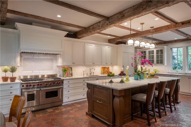 kitchen with range with two ovens, white cabinetry, a center island, and sink