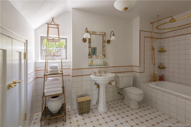 full bathroom with tiled shower / bath, vaulted ceiling, sink, tile walls, and toilet