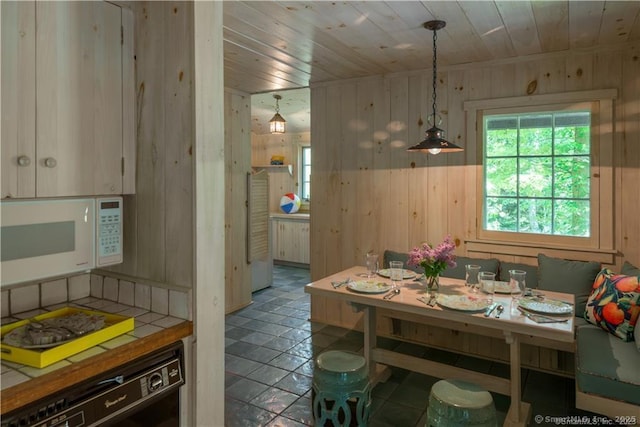 dining room featuring wood ceiling and wooden walls