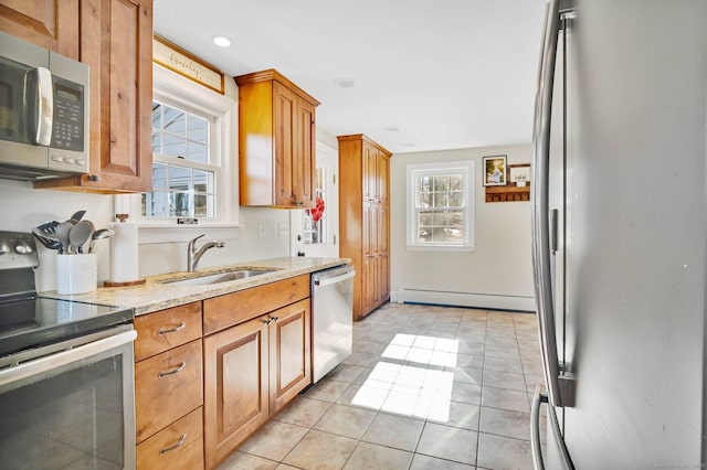 kitchen featuring sink, light tile patterned floors, appliances with stainless steel finishes, light stone countertops, and a baseboard heating unit