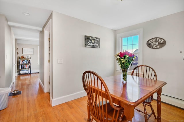 dining space with light wood-type flooring and baseboard heating