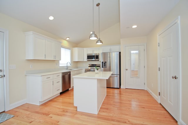 kitchen with a kitchen island, appliances with stainless steel finishes, pendant lighting, white cabinetry, and sink