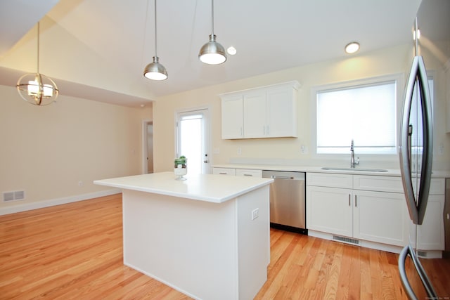 kitchen featuring sink, appliances with stainless steel finishes, hanging light fixtures, a center island, and white cabinets