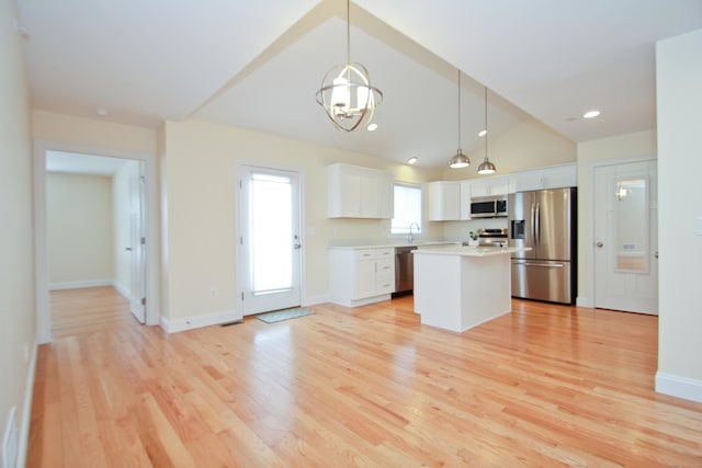 kitchen featuring pendant lighting, white cabinetry, a center island, stainless steel appliances, and light hardwood / wood-style flooring