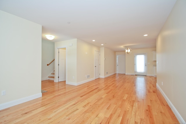 spare room with a notable chandelier and light hardwood / wood-style flooring