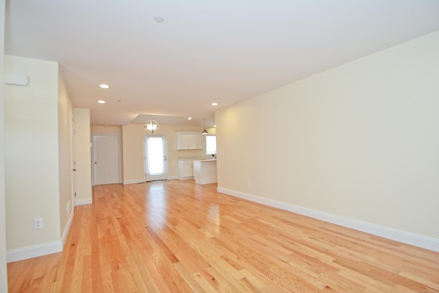 unfurnished living room with a chandelier and light wood-type flooring