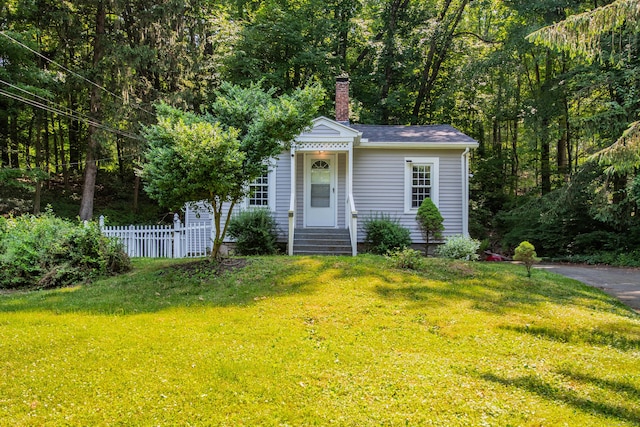 view of front of home with entry steps, a chimney, fence, and a front yard