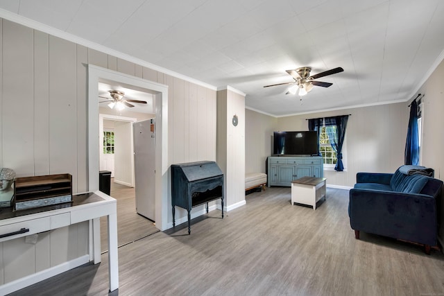 living room featuring baseboards, crown molding, a ceiling fan, and wood finished floors