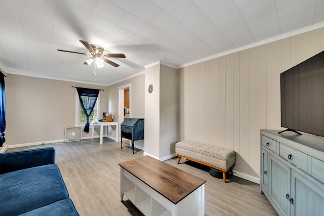 living area featuring a ceiling fan, baseboards, ornamental molding, light wood-type flooring, and radiator