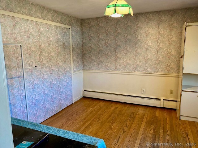 unfurnished room featuring baseboard heating and hardwood / wood-style flooring