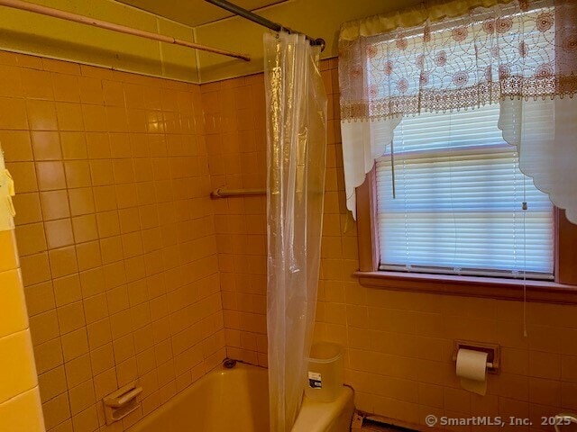 bathroom with shower / tub combo and tile walls