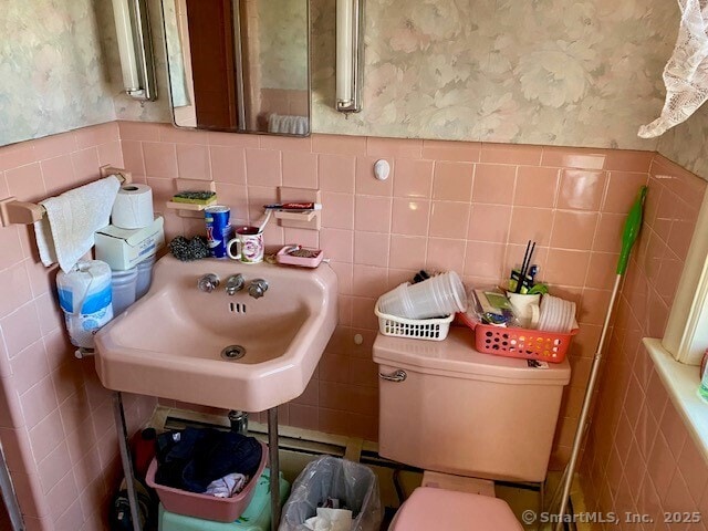 bathroom featuring tile walls, sink, and toilet