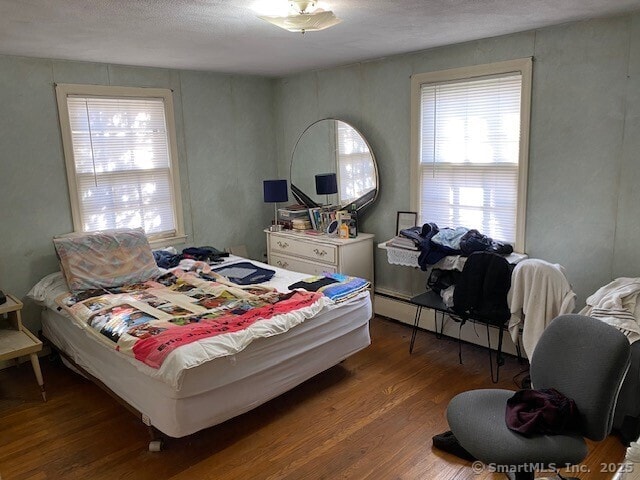 bedroom featuring hardwood / wood-style flooring and baseboard heating