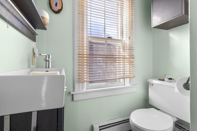 bathroom with a wealth of natural light, baseboard heating, and toilet