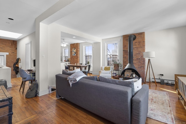 living room with wood-type flooring, brick wall, and a wood stove