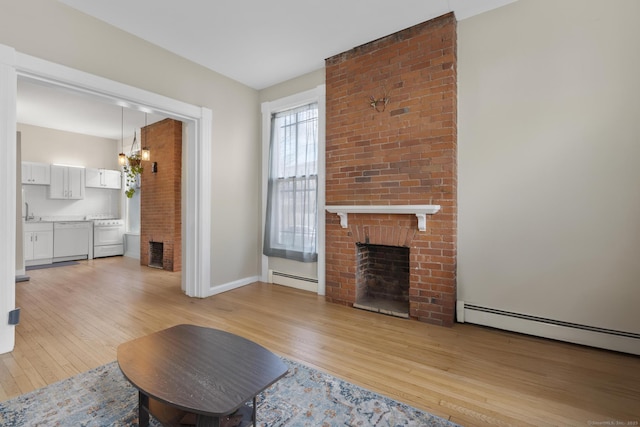 unfurnished living room featuring a fireplace, light hardwood / wood-style flooring, and a baseboard radiator