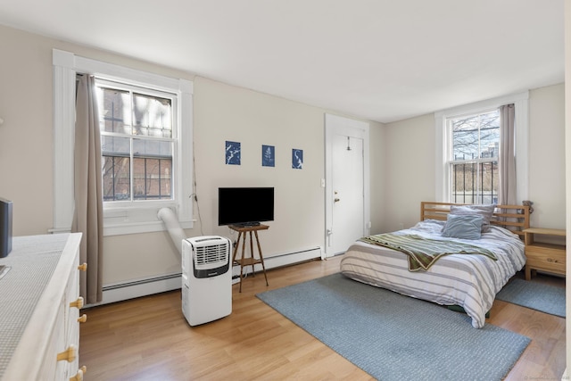 bedroom with a baseboard radiator and light hardwood / wood-style floors