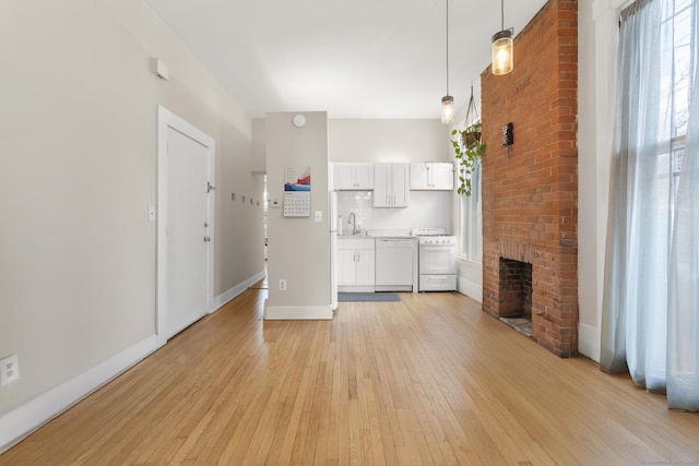 unfurnished living room featuring sink, a fireplace, and light wood-type flooring