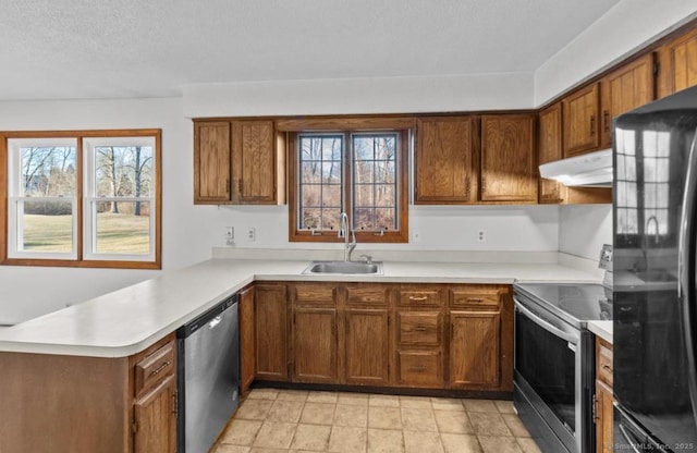 kitchen with sink, kitchen peninsula, a textured ceiling, and appliances with stainless steel finishes