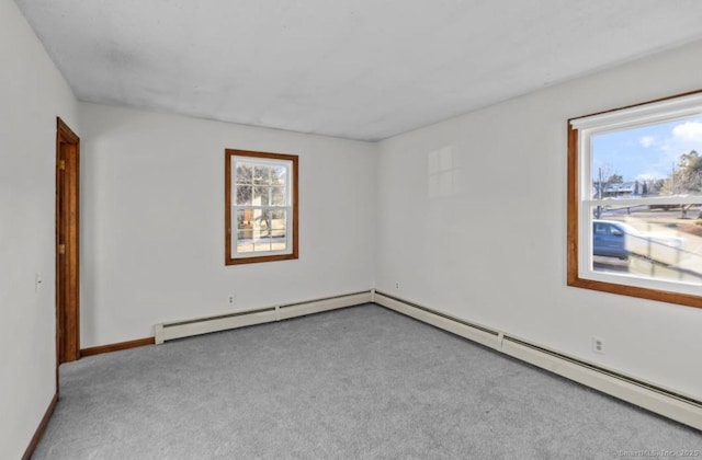 empty room featuring light colored carpet, plenty of natural light, and a baseboard heating unit