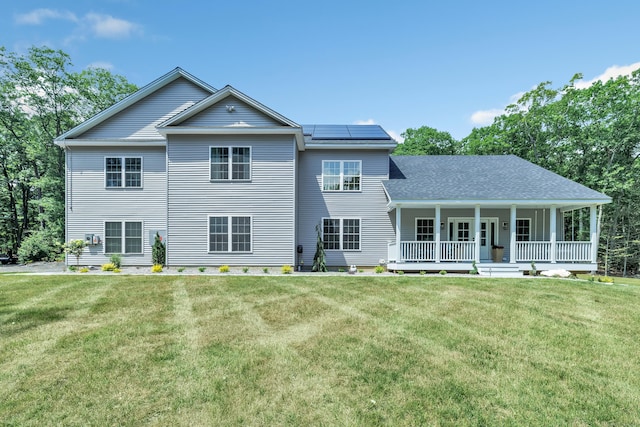 rear view of property with a porch, a lawn, and solar panels