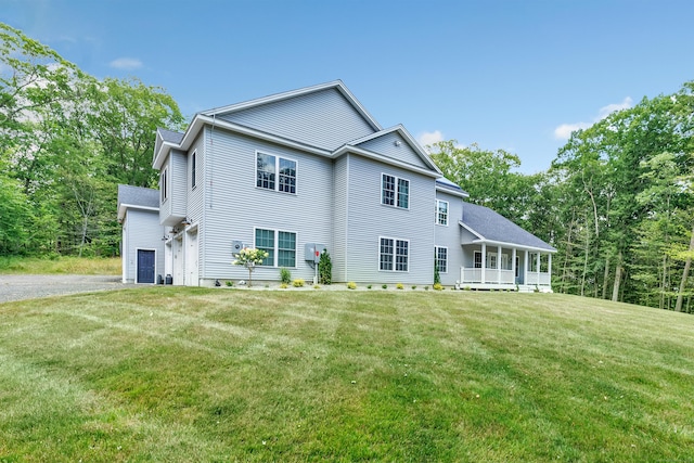 back of property featuring a garage, a yard, and covered porch