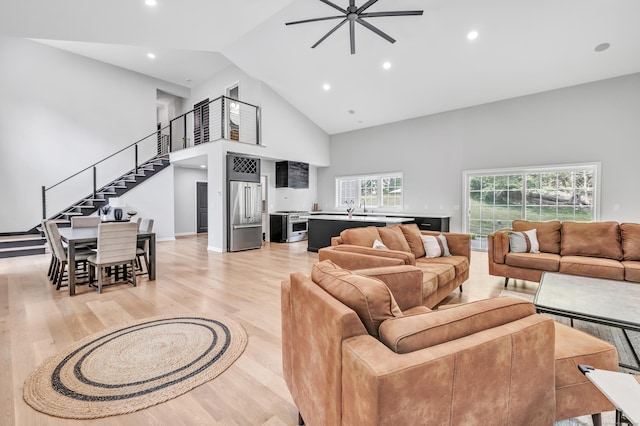 living room with ceiling fan, high vaulted ceiling, sink, and light hardwood / wood-style floors