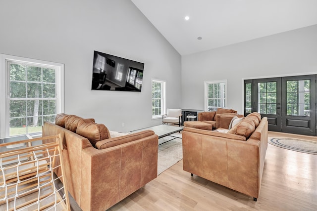 living room with french doors, high vaulted ceiling, and light hardwood / wood-style flooring