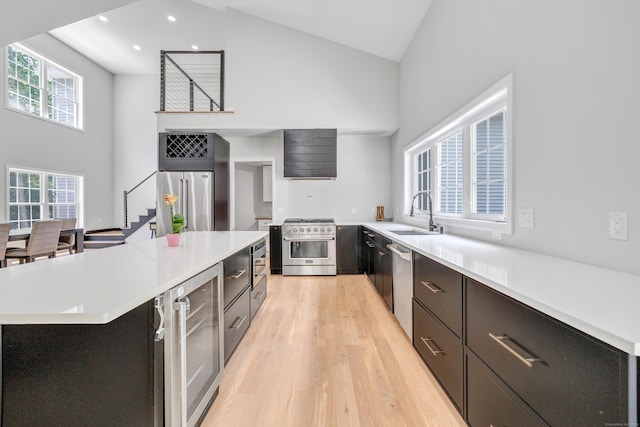 kitchen with sink, high vaulted ceiling, high quality appliances, wine cooler, and a kitchen island