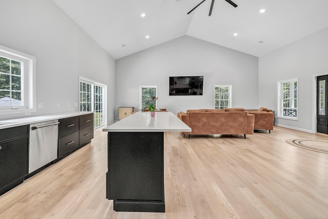 kitchen with high vaulted ceiling, light wood-type flooring, stainless steel dishwasher, a kitchen island, and ceiling fan