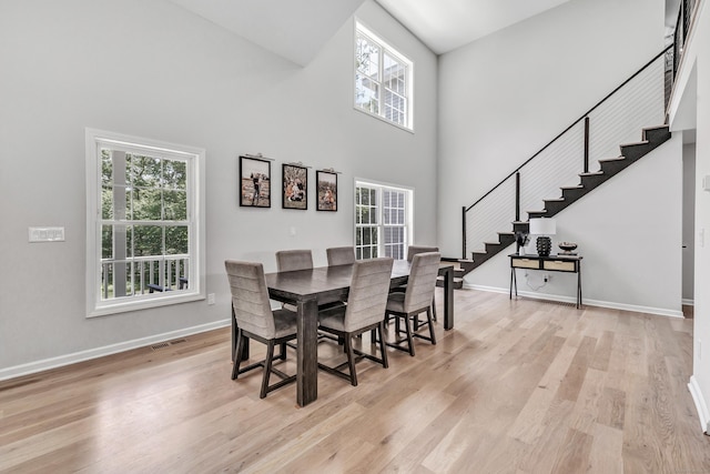 dining area featuring a high ceiling, a healthy amount of sunlight, and light wood-type flooring