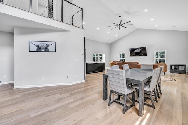 dining room with ceiling fan, high vaulted ceiling, and light wood-type flooring