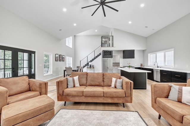 living room featuring french doors, sink, high vaulted ceiling, light hardwood / wood-style flooring, and ceiling fan