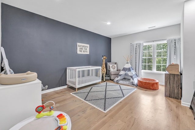 bedroom with a crib and light wood-type flooring