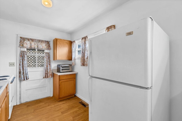 kitchen with a toaster, visible vents, range, freestanding refrigerator, and light wood-type flooring