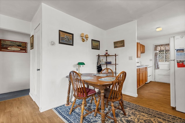 dining area featuring light wood-style flooring and baseboards