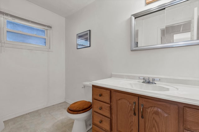 bathroom featuring baseboards, vanity, and toilet