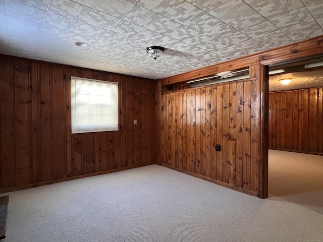 carpeted empty room featuring wood walls