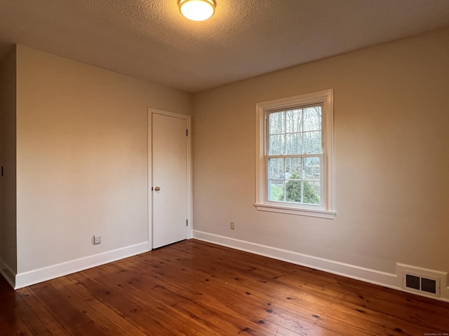 empty room with dark hardwood / wood-style flooring and a textured ceiling