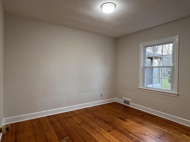 empty room with hardwood / wood-style flooring and a textured ceiling