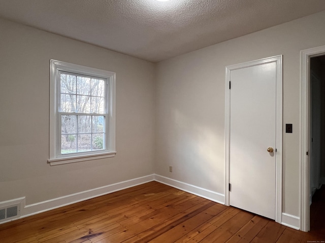 unfurnished room with hardwood / wood-style flooring and a textured ceiling