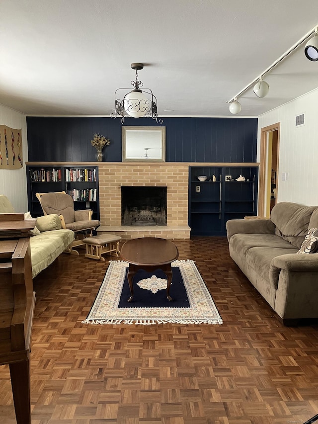 living room with a brick fireplace, dark parquet floors, and rail lighting